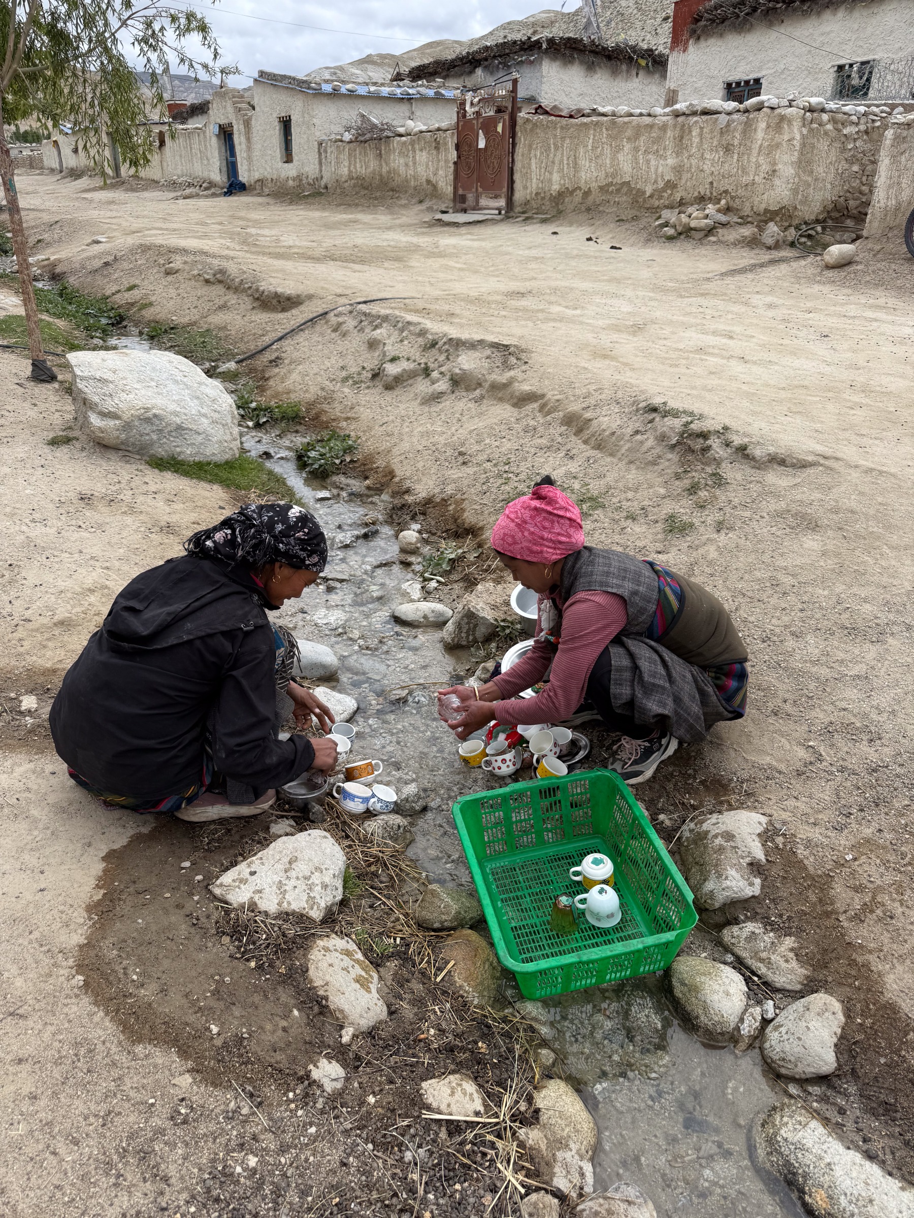 Two women in traditional dress rinse teacups in a mountain stream in Namashung, Upper Mustang, Nepal.

life in remote Himalayan communities such as Namashung relies on natural systems for resources such as clean flowing water. This reliance is woven into the most basic routines of domestic life of these villages and the gendered labour of the women within them.

As climate change alters precipitation patterns, threatens glacial water sources, and increases the unpredictability of mountain streams, it is communities like this who will feel the most immediate effects of a disrupted water supply.